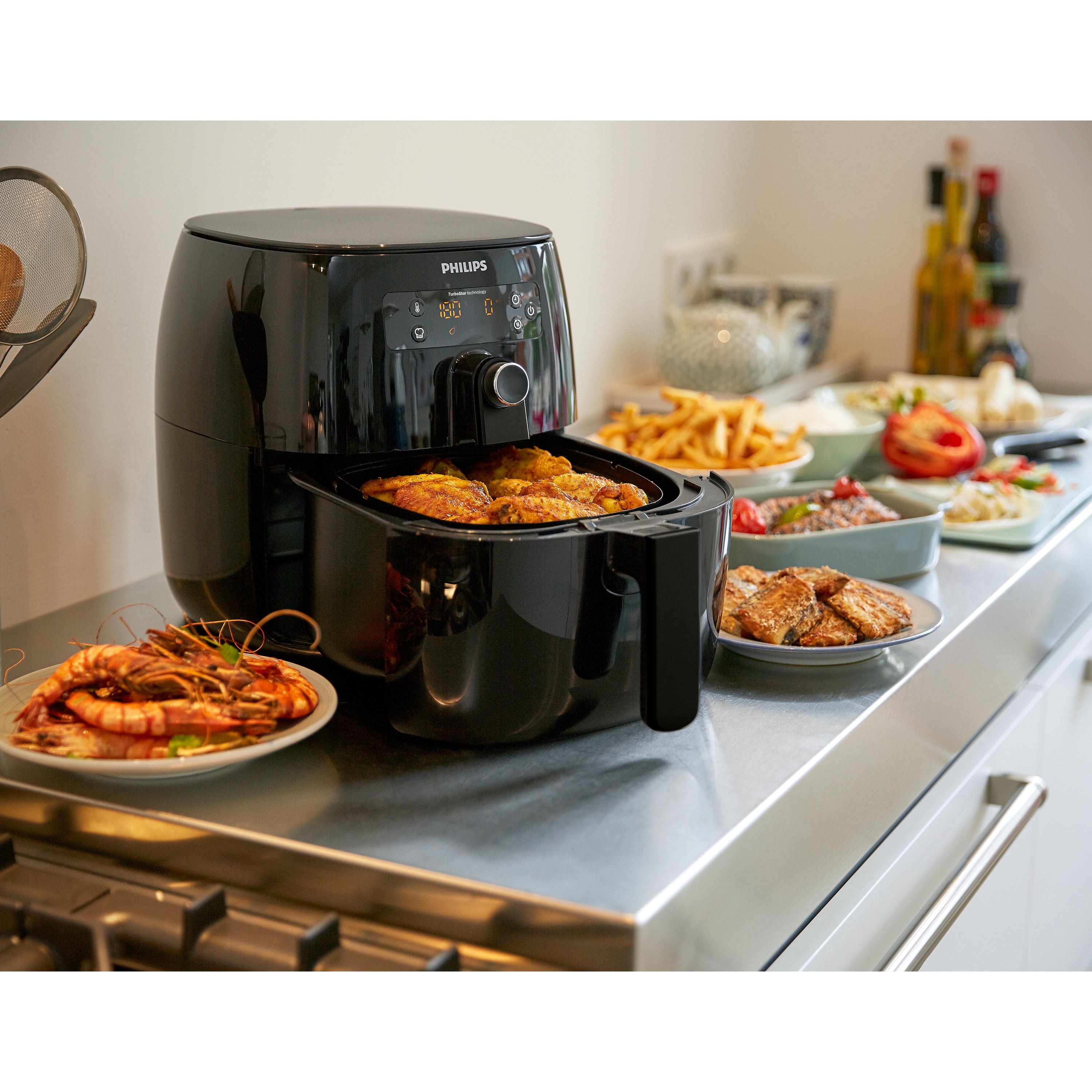 Philips air fryer on a kitchen counter with various dishes around it.