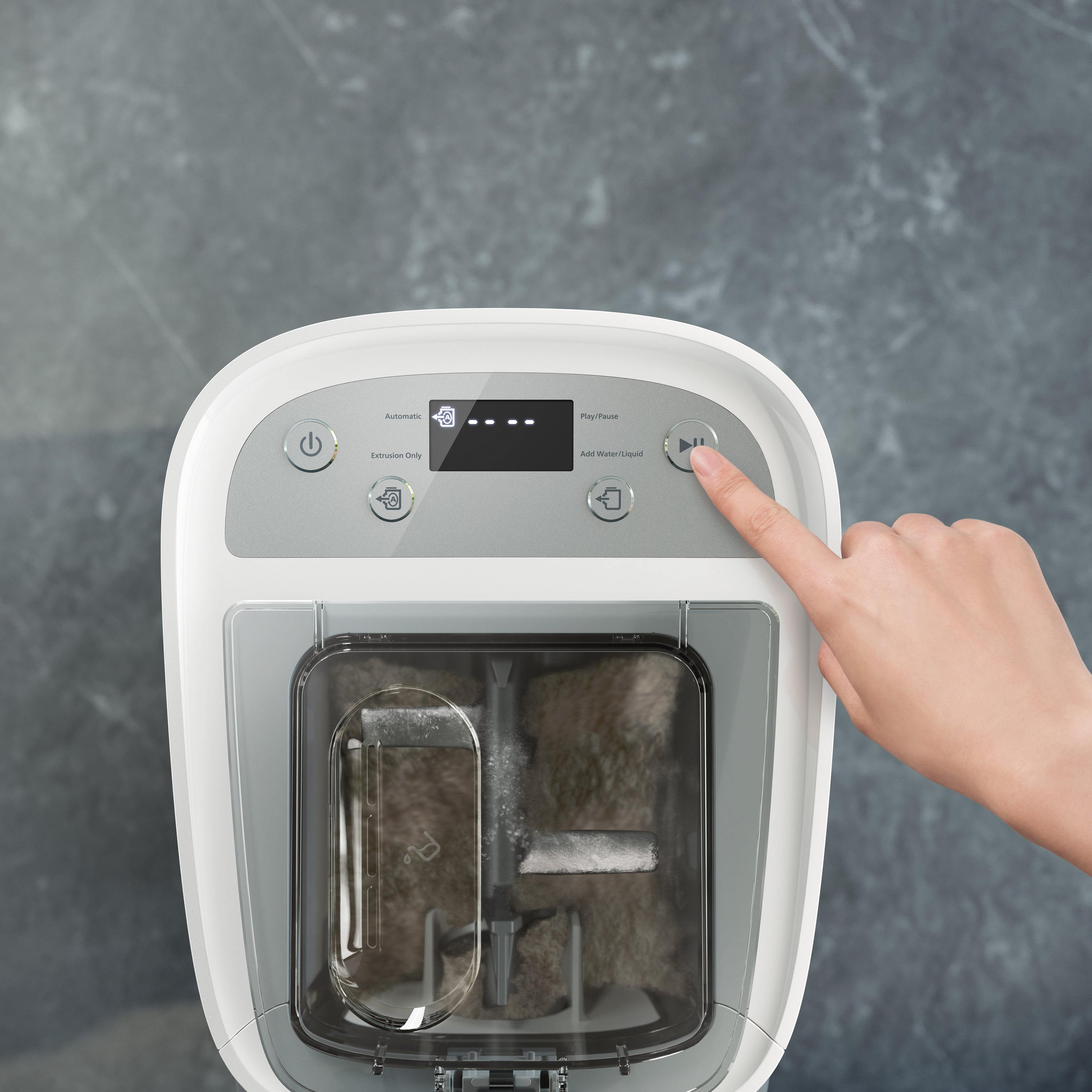 Hand pressing a button on a white electronic pasta maker with a screen against a gray background