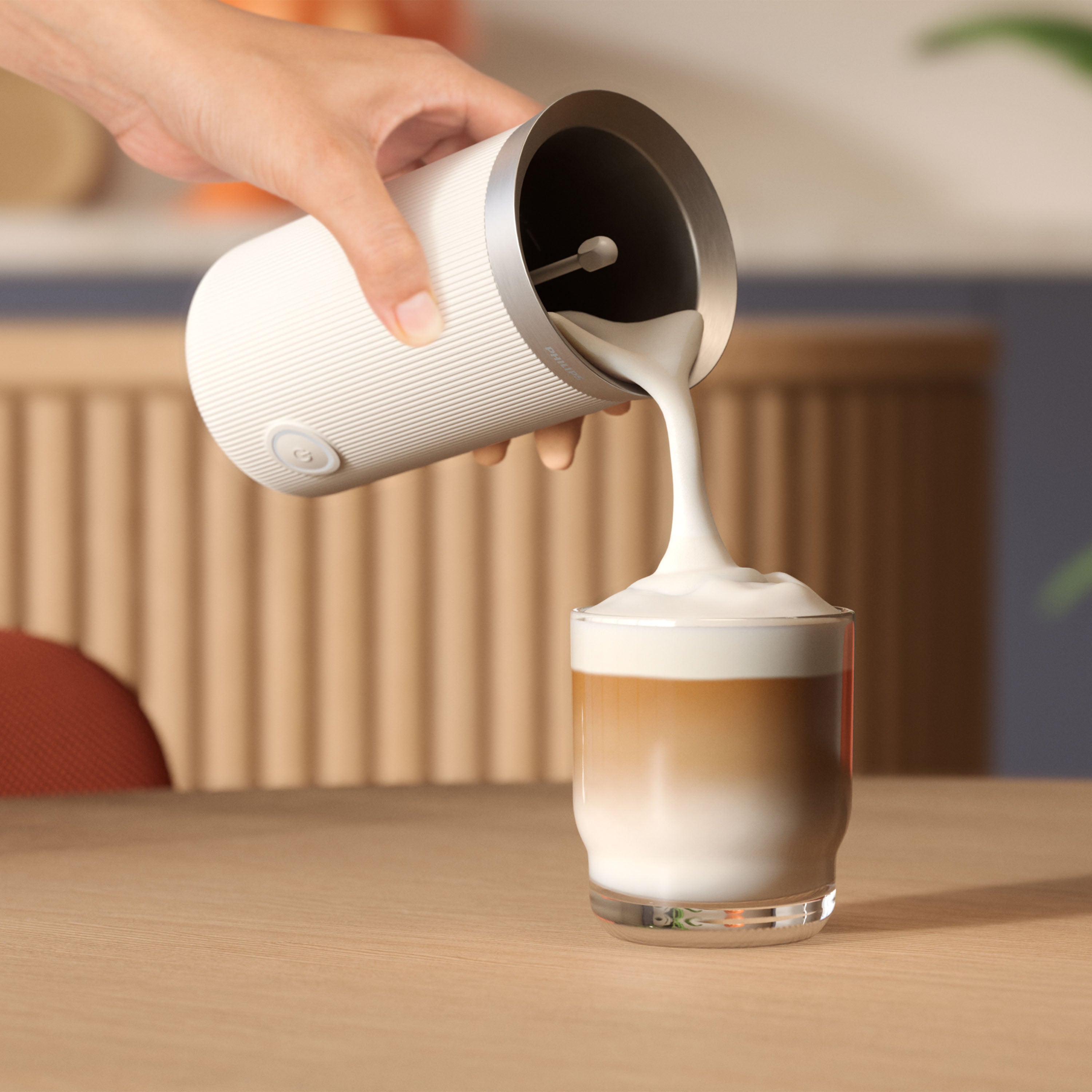 Philips milk frother pouring creamy, textured milk into a glass.