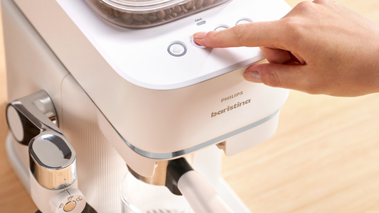 A hand pressing a button on the a coffee machine. 