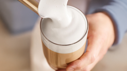 Pouring froth on top of coffee.