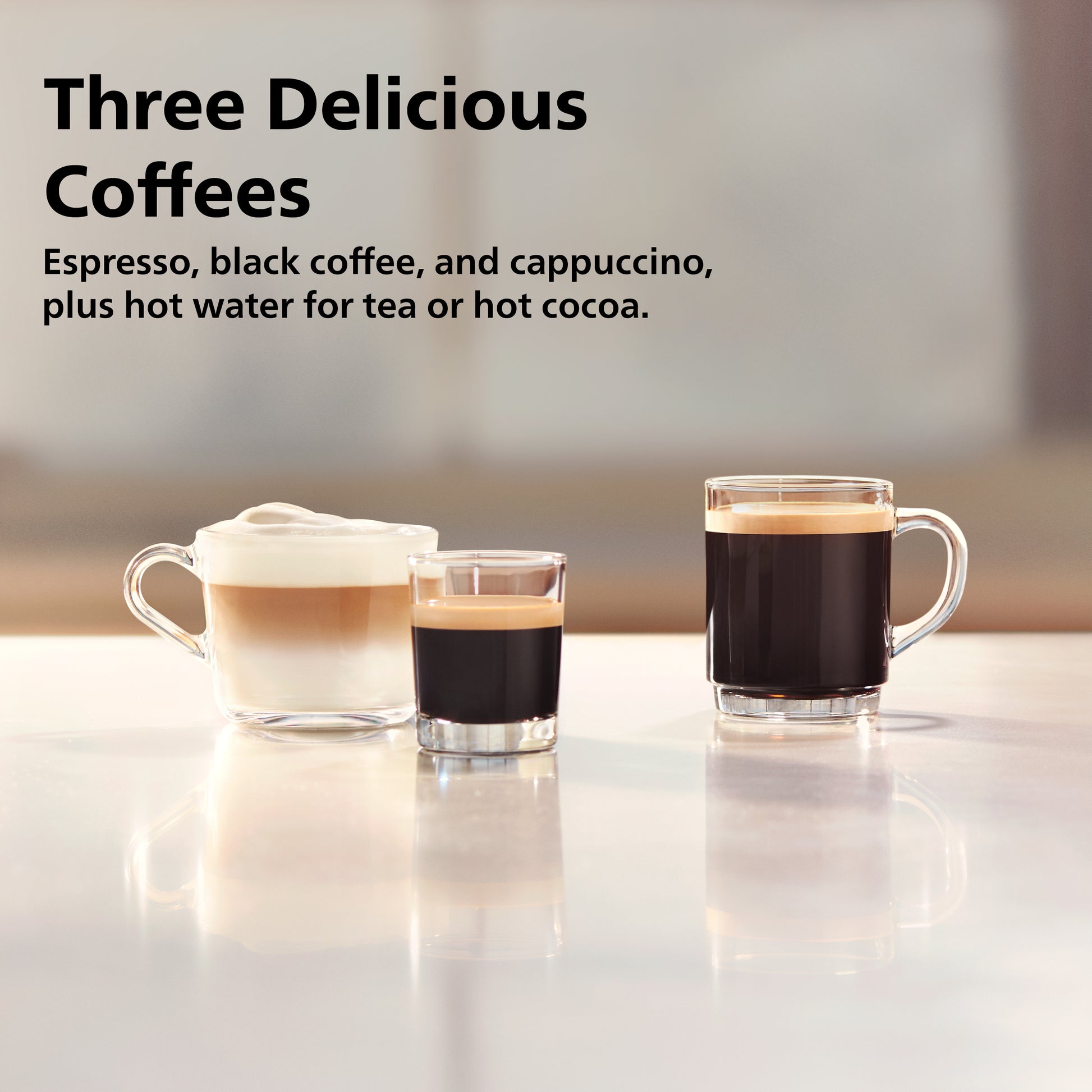 Three glasses of different coffee types on a reflective surface with a blurred background.