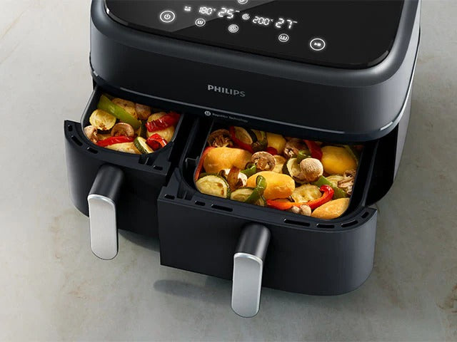 Philips air fryer with food inside on a light gray background