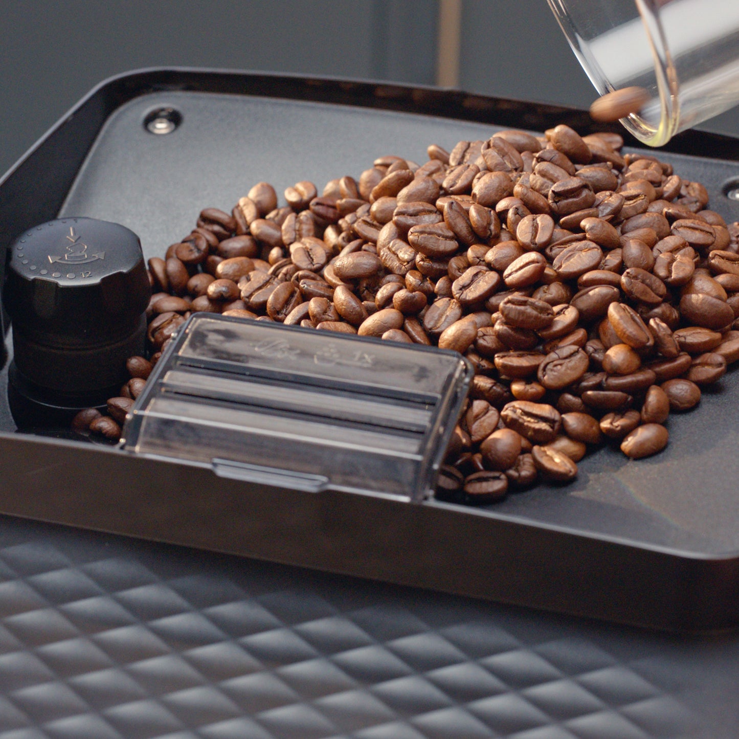 Coffee beans on a tray with a coffee grinder