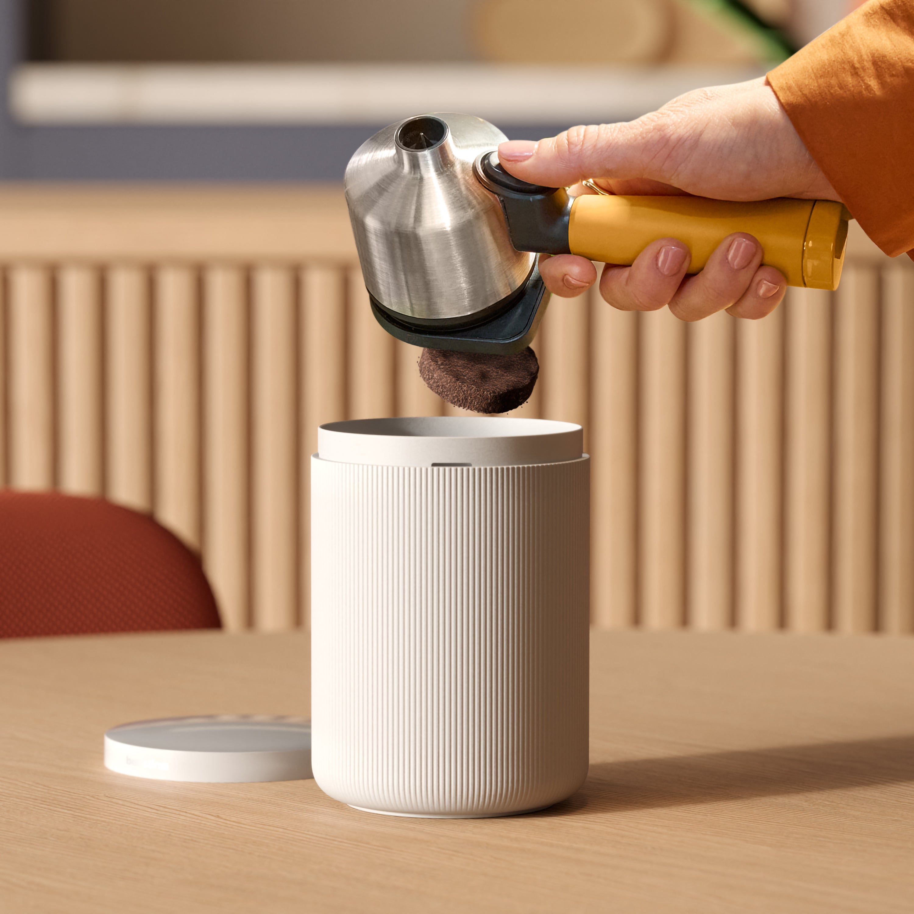 Person using a portafilter dumping coffee ground in a bin.