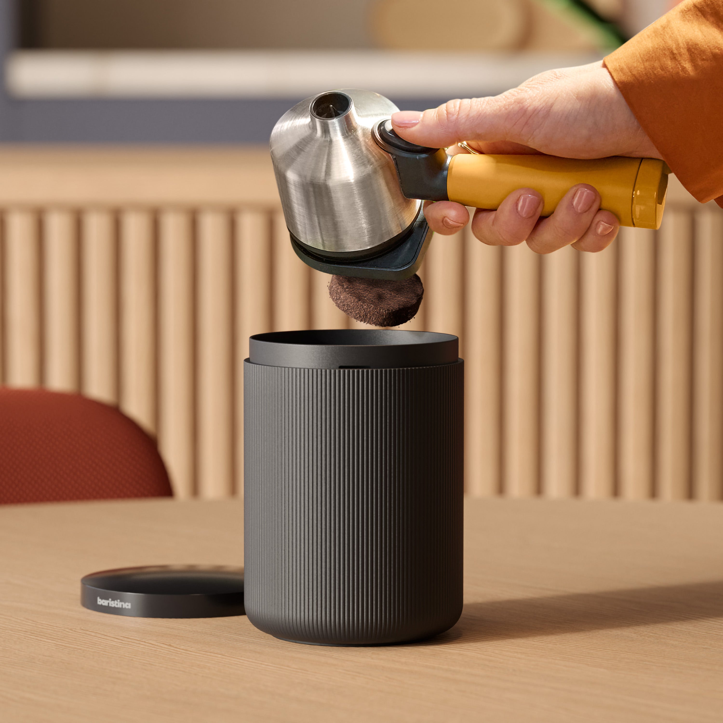 Person using a portafilter dumping coffee grounds in bin.