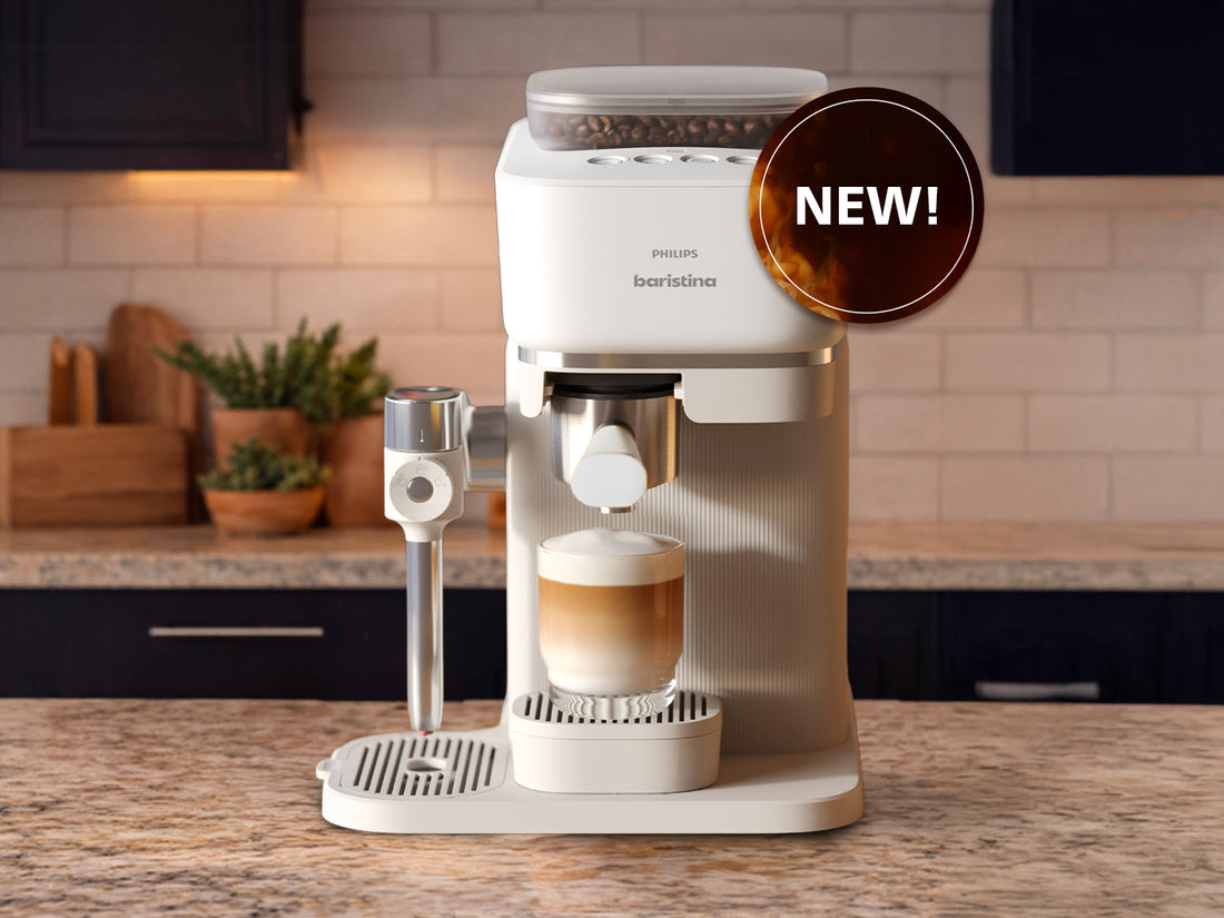 White espresso machine with a glass of coffee on a wooden countertop in a kitchen.