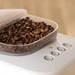 Coffee grinder with coffee beans inside on a beige background