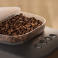 Coffee grinder with a container of coffee beans on a wooden background