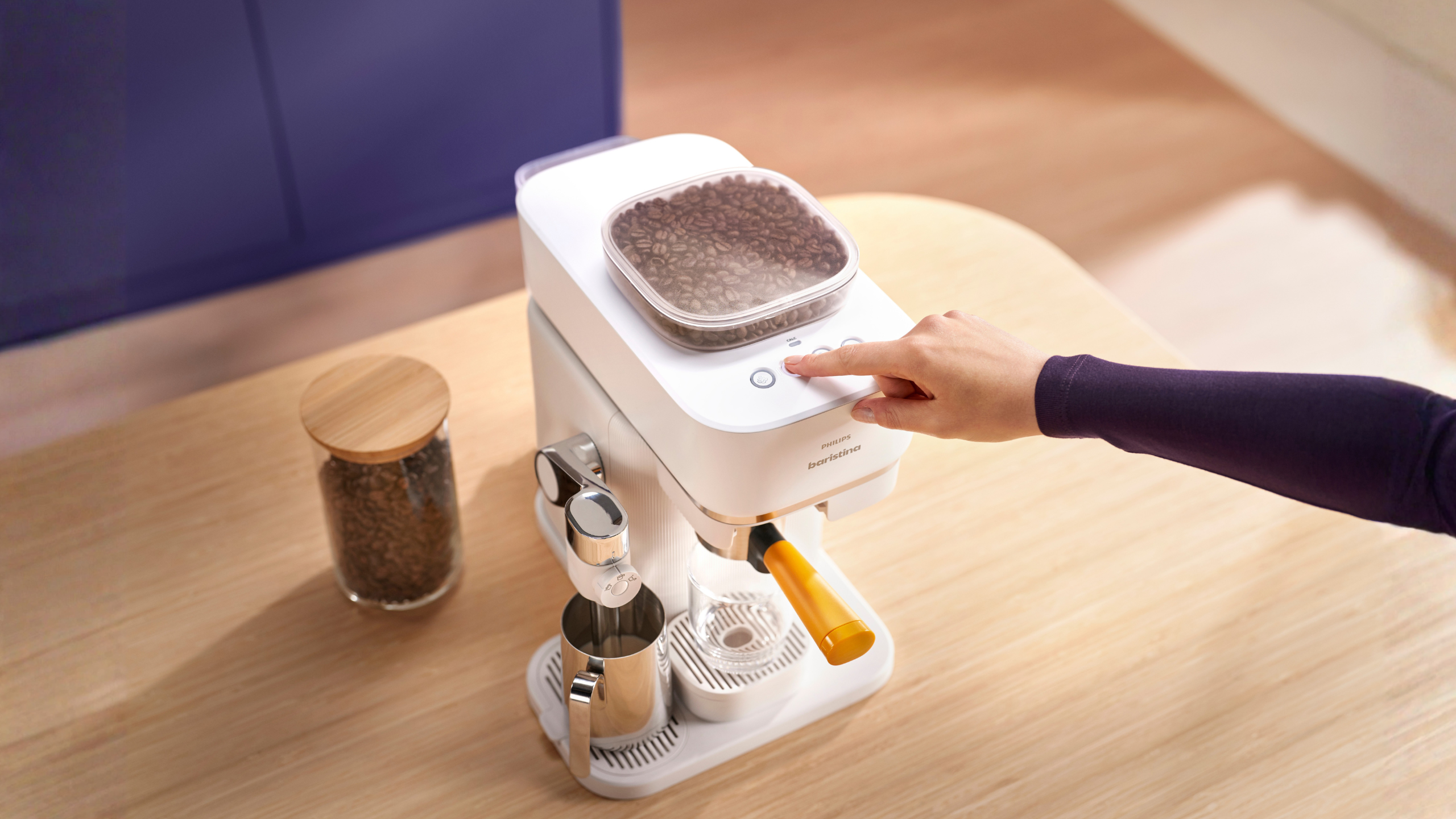 White kitchen appliance on a wooden surface with a hand interacting with it.