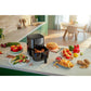 Black air fryer on a kitchen counter with various food items around it.