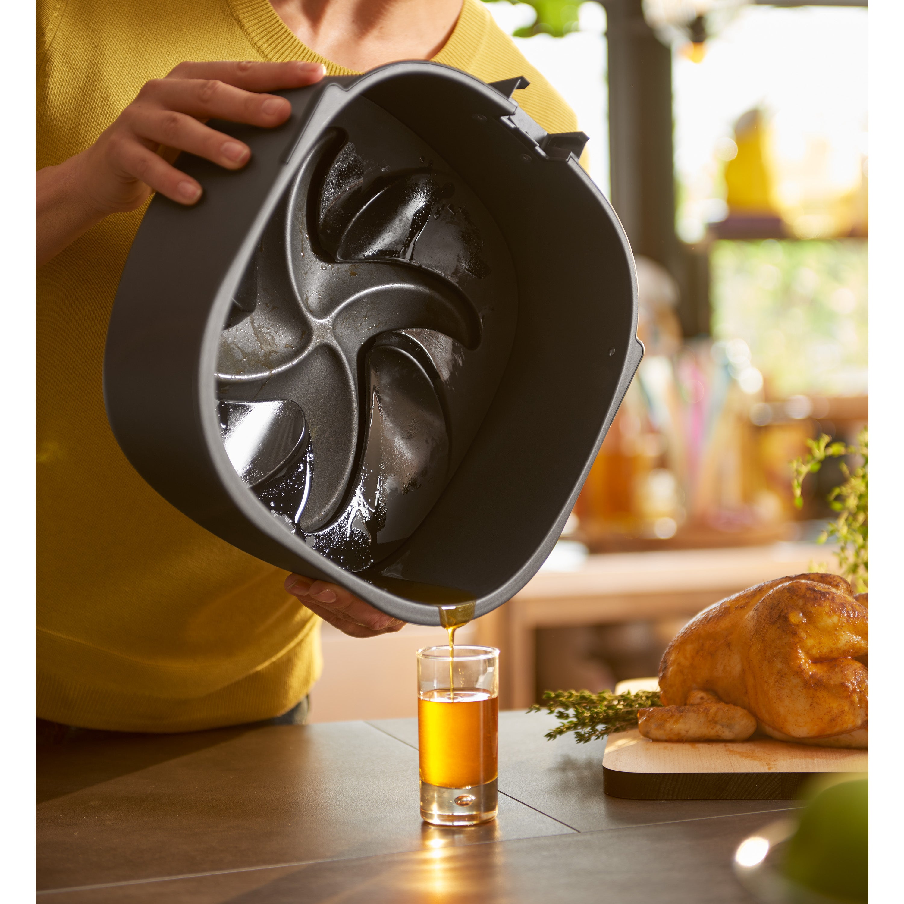 Person pouring a oil into a glass with that came from the airfryer