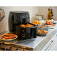 Philips air fryer on a kitchen counter with various dishes around it.