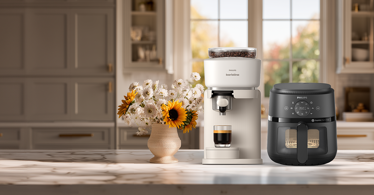 Kitchen scene with a coffee maker and air fryer on a countertop, featuring a vase of flowers.